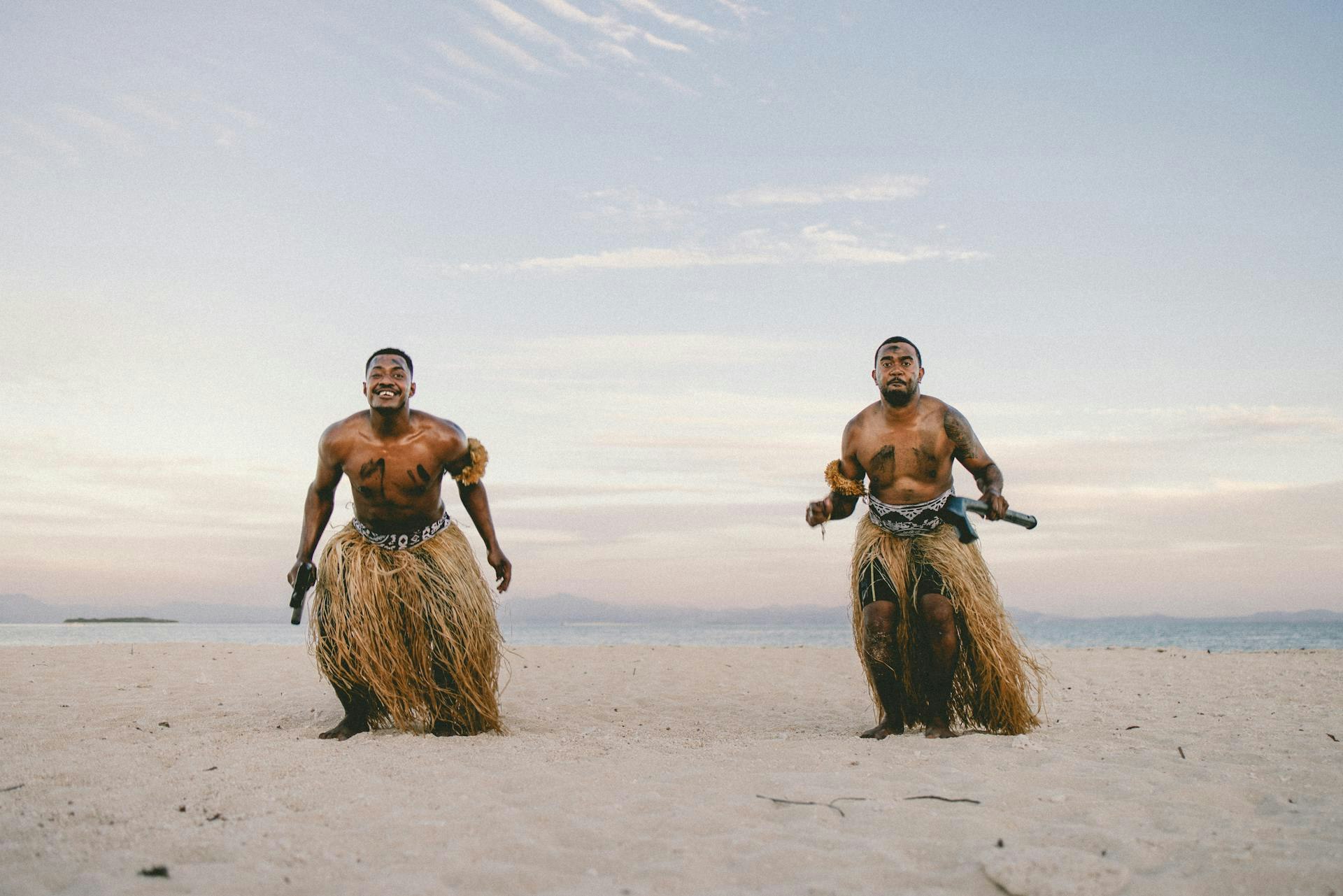 Two people in traditional garments standing on a beach