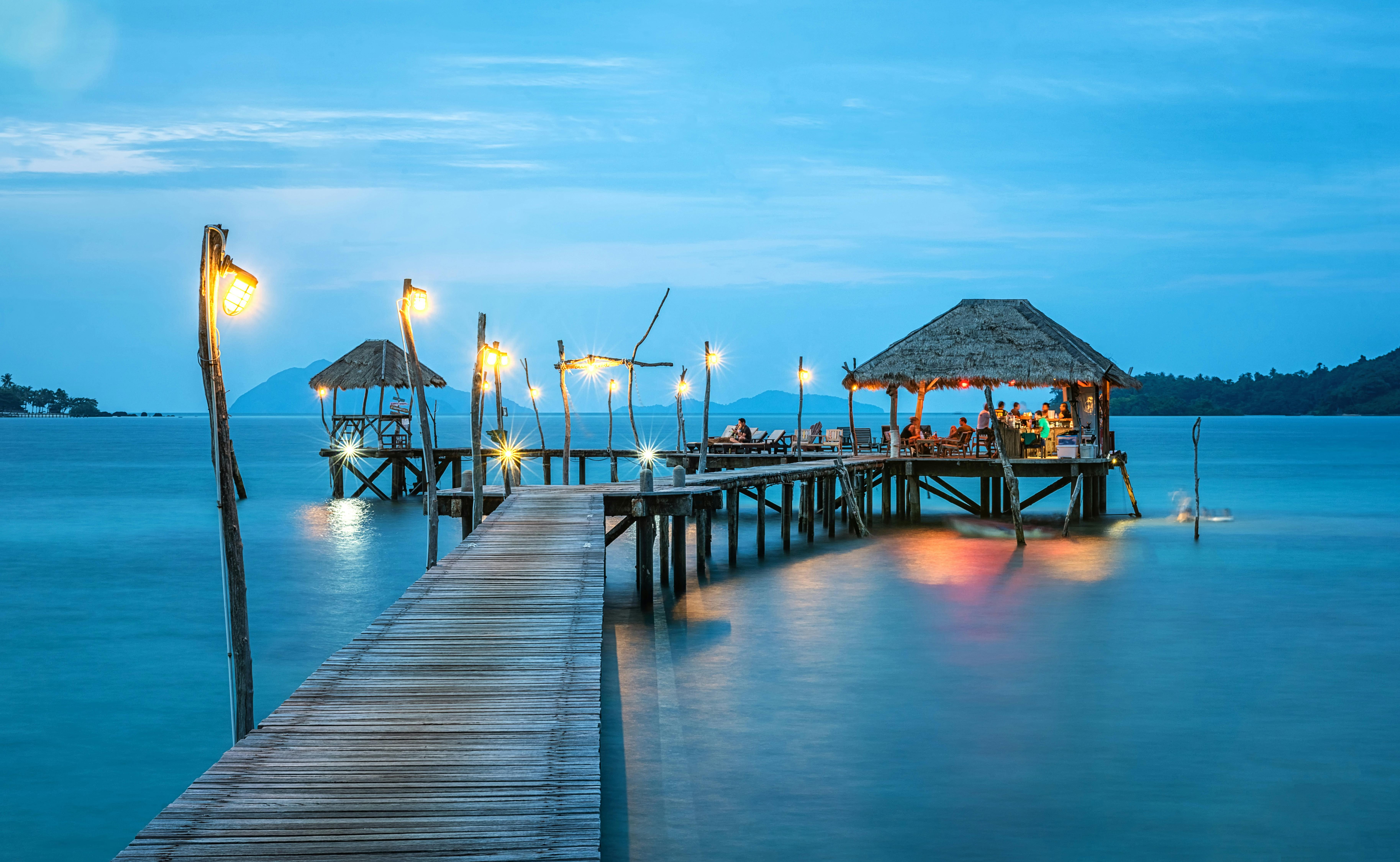 brown wooden bridge and hut standing on the sea
