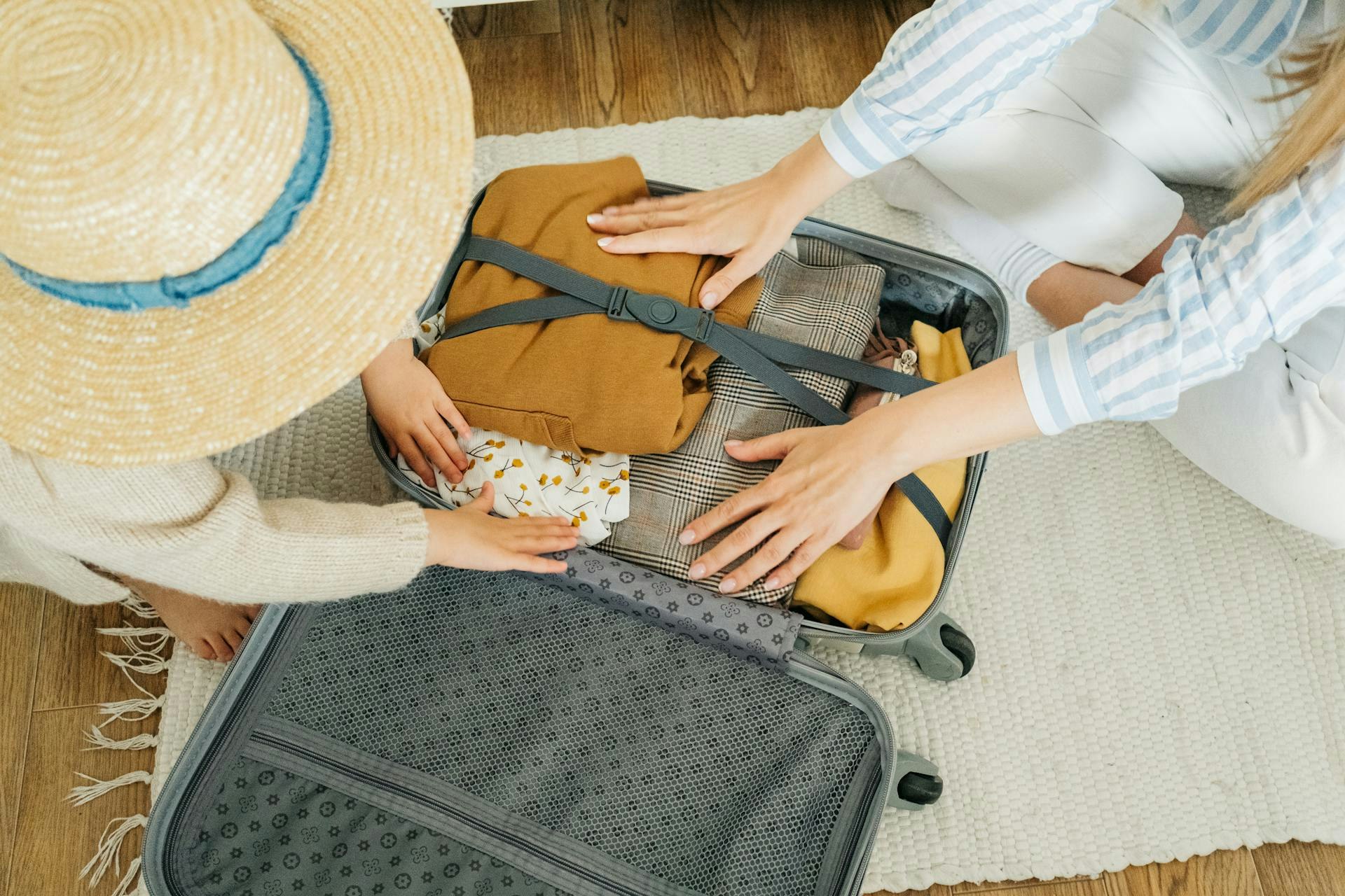 Two people packing clothes in a suitcase