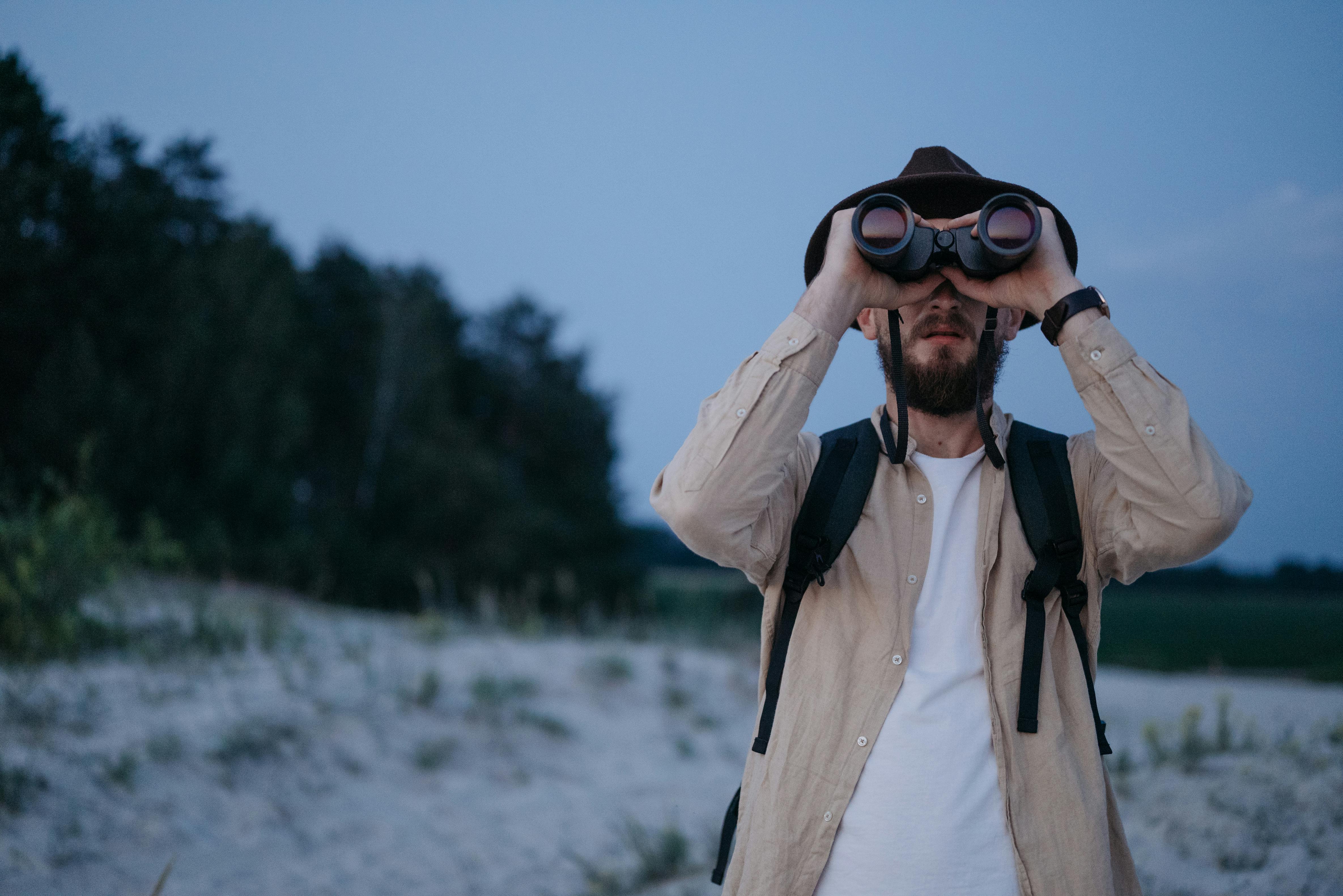 A man at the beach looking through binoculars
