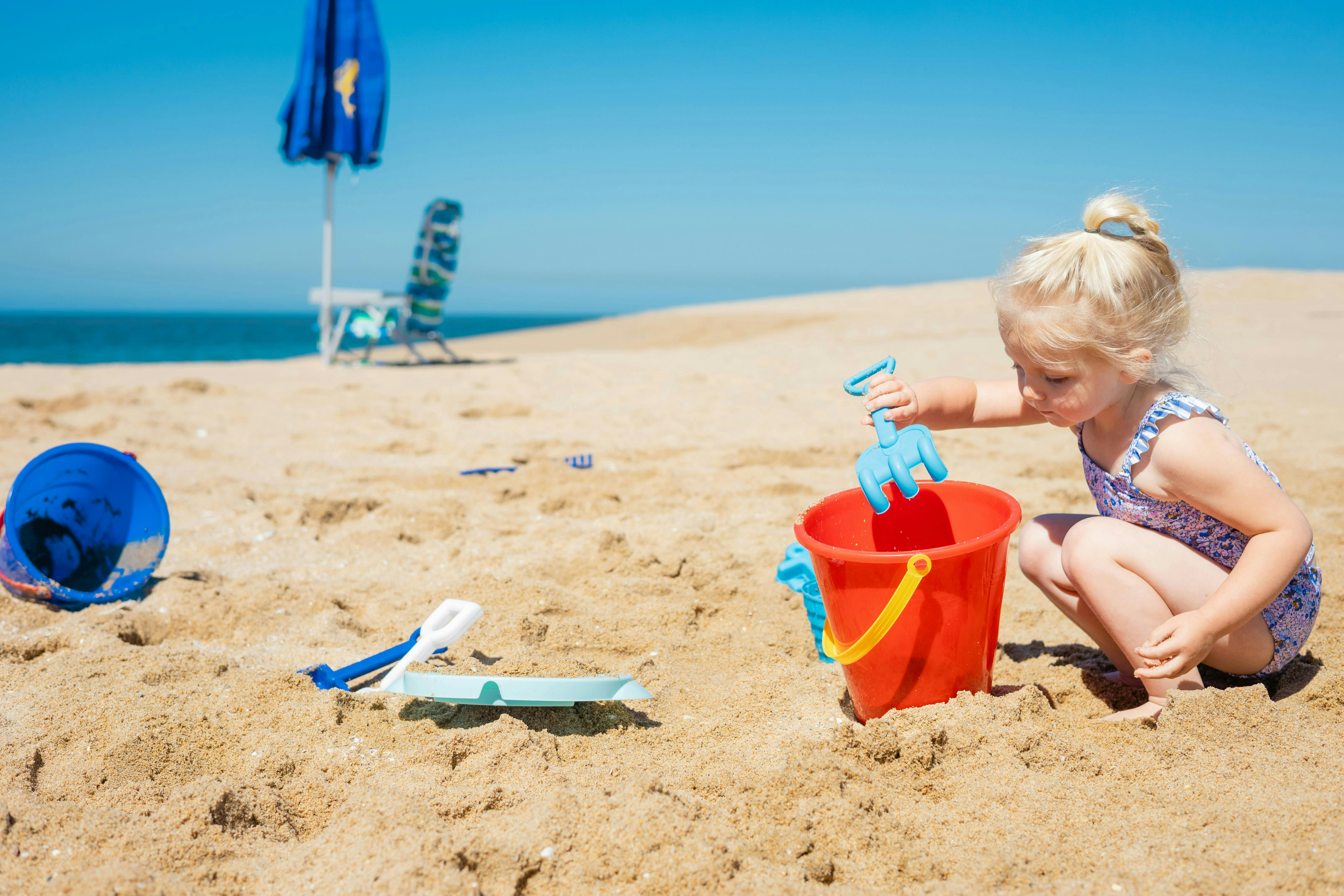 a little girl playing with her toys on the beach