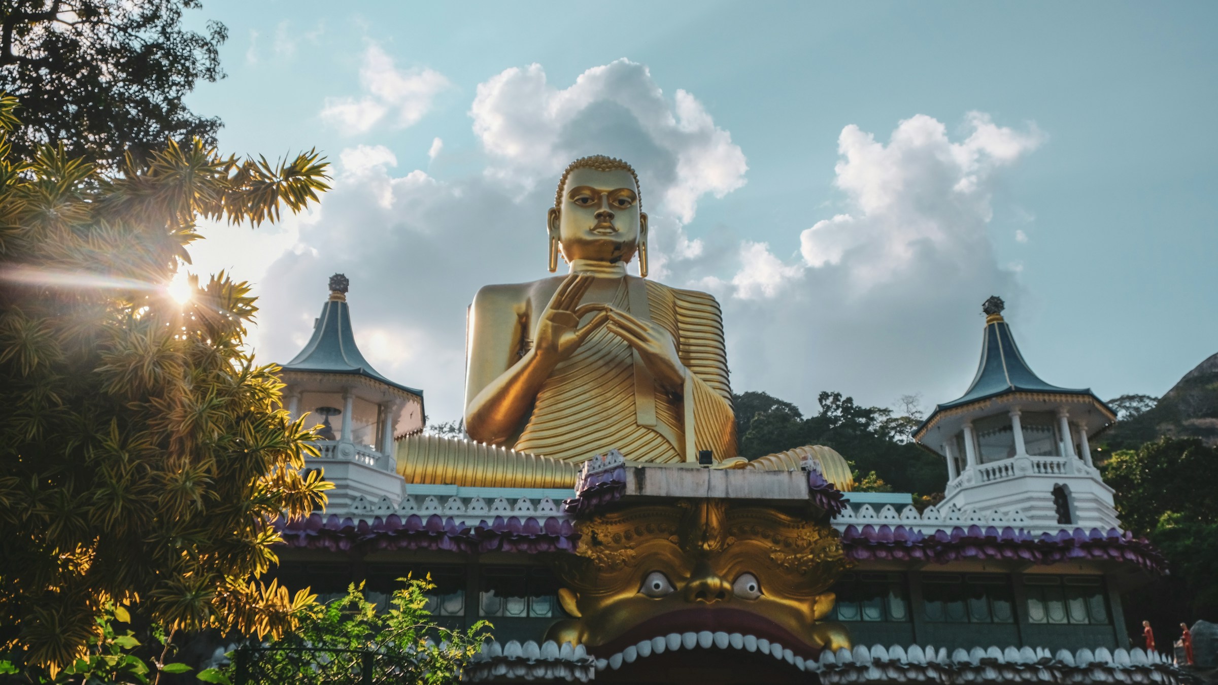 A gold Buddha statue under a cloudy sky during daytime surrounded by pagodas