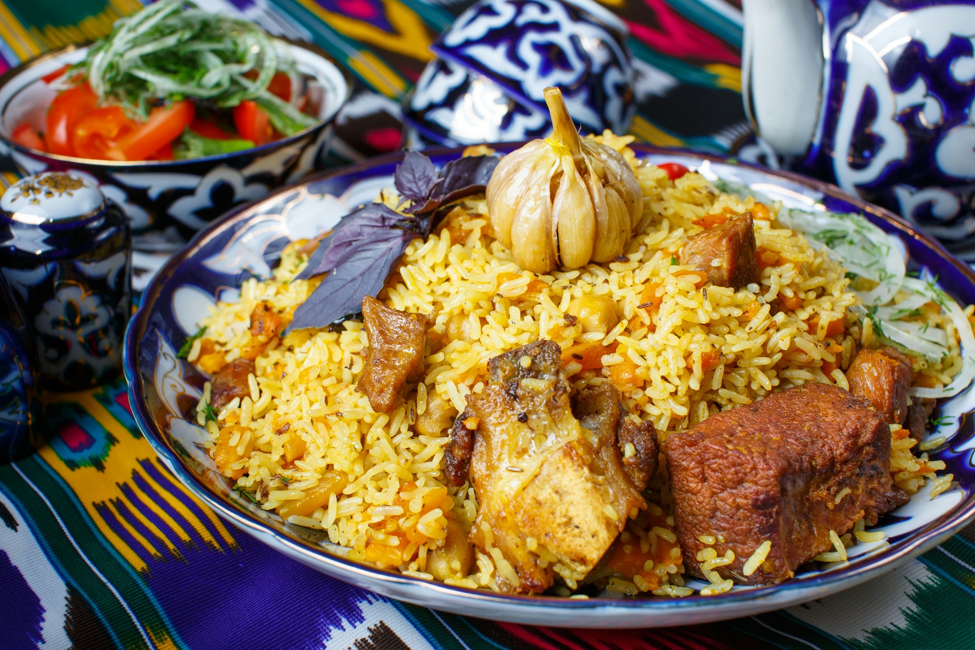 A plate of golden, fried pilaf with meat and roasted garlic, similar to Uzbekistan’s rice dish “plov.”