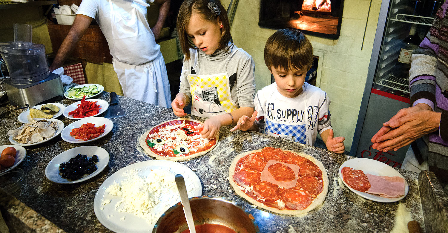 Kids learning how to make pizza.